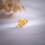 Close-up of floral 18K gold nose pin placed on a soft surface highlighting its intricate cutwork design