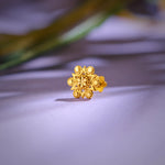 Floral cluster 18K nose pin gold placed on a soft lavender surface highlighting its detailed craftsmanship