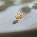 Single stone nose pin gold with round diamond solitaire in prong setting on soft grey background