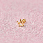 Gold crown-shaped nose stud on pink glitter background