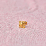 Gold floral cutwork nose stud in diamond shape on pink glitter background