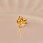 Gold trishul trident-shaped nose stud on beige background