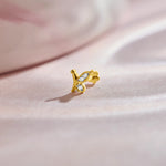 Nose pin of gold with butterfly inspired diamond design on soft pink fabric background