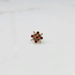 A gold nose pin shaped like a flower, set with ruby-red and clear crystal stones