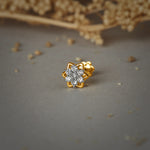 Nose pin gold with floral star design featuring sparkling stones set in a polished gold base on a soft neutral background
