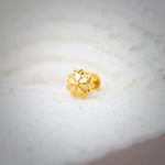 Close-up of floral-shaped 18K nose pin gold placed on a soft white surface highlighting its intricate detailing
