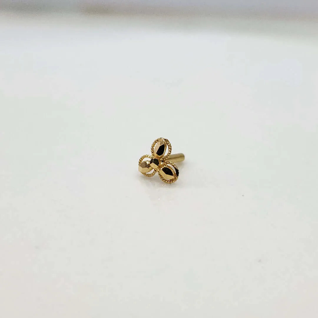 Close up view of a tiny 18K nose pin gold placed on a white surface highlighting its compact size and polished finish