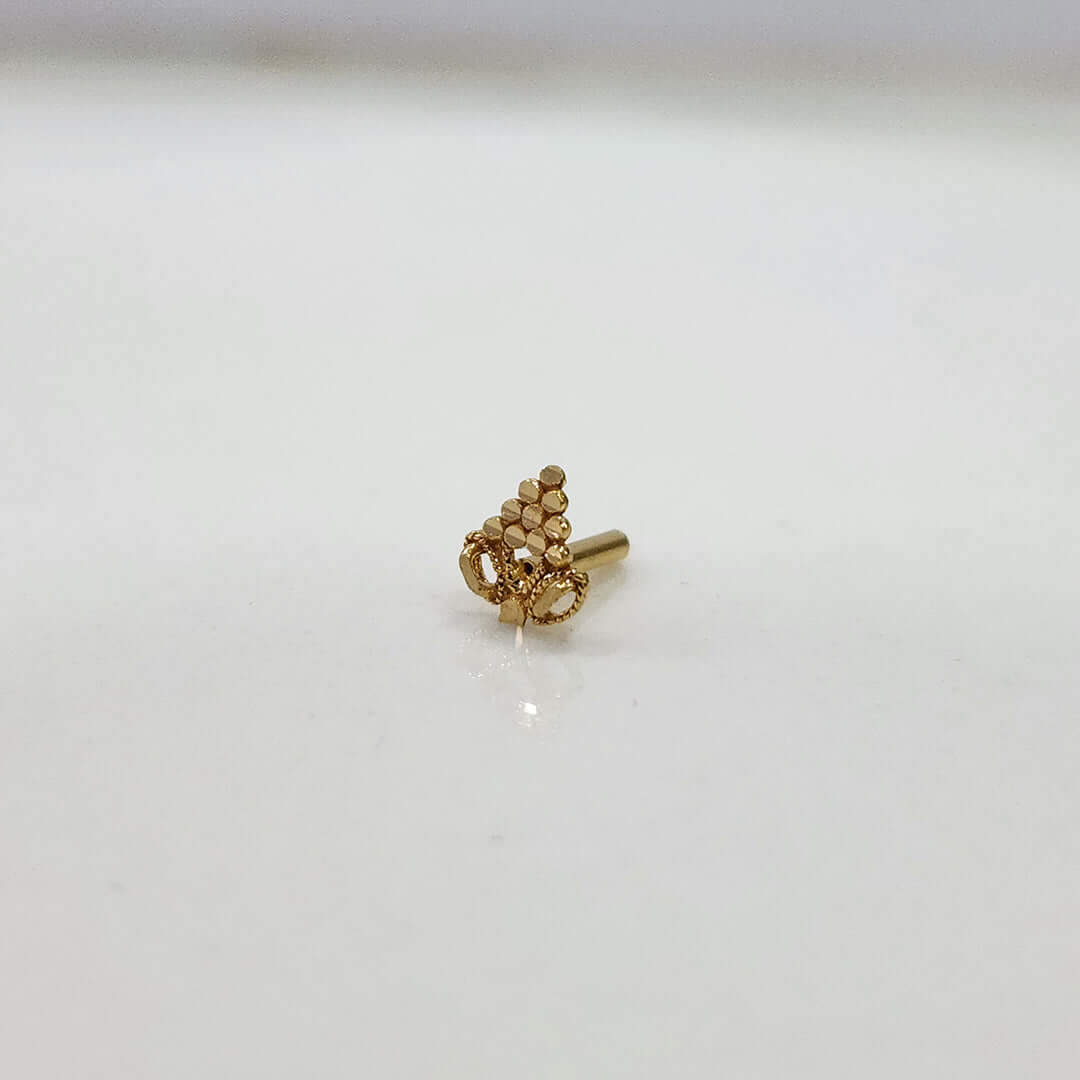Close-up of tiny 18K gold nose pin on a white background highlighting its fine detailing