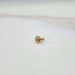Side view of a tiny gold nose pin on a white surface highlighting its lightweight structure and polished finish