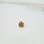 Side angled view of a tiny heart shaped gold nose pin on a white surface highlighting its polished finish