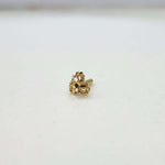 Side angle view of the floral gold nose pin on a white surface highlighting its depth and polished finish