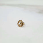 Close-up of a delicate 18K nose pin gold placed on a white surface showing fine craftsmanship and polished finish
