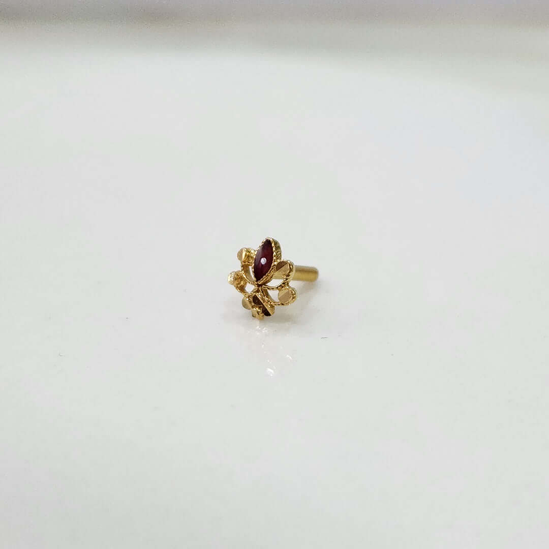 Close up of tiny floral 18K gold nose pin placed on a white surface highlighting its detailed design