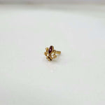 Close up of tiny floral 18K gold nose pin placed on a white surface highlighting its detailed design