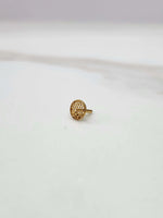 Side view of a small round 18K gold nose pin placed on a white surface showcasing its compact size and polished finish