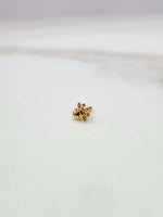 Side view of a delicate 18K nose pin gold placed on a white surface showcasing its fine finish and minimal detailing
