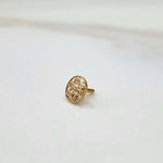 Side view of a delicate 18K gold round-pattern nose pin placed on a white surface highlighting its detailing