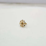 Close-up of tiny floral 18K gold nose pin placed on a white background highlighting its fine detailing