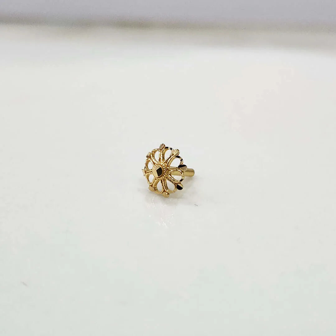 Close-up of tiny floral 18K gold nose pin placed on a white background highlighting its fine detailing