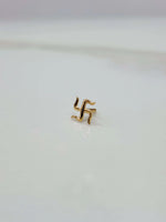 Close up of a small swastik 18K nose pin gold placed on a white surface showing fine detailing and compact size