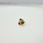 Front view of floral gold nose pin with green and red stone detailing on a white surface