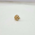 Small floral 18K nose pin gold placed on a white surface showing its fine handcrafted detailing