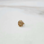 Side view of a small round 18K gold nose pin placed on a white surface showing its post and finish