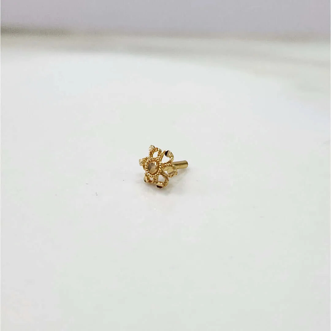 Front view of small floral gold nose pin on a white background showing compact size and fine detailing