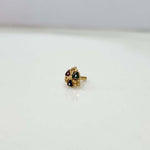 Front view of floral gold nose pin with green and red stones on a plain white surface