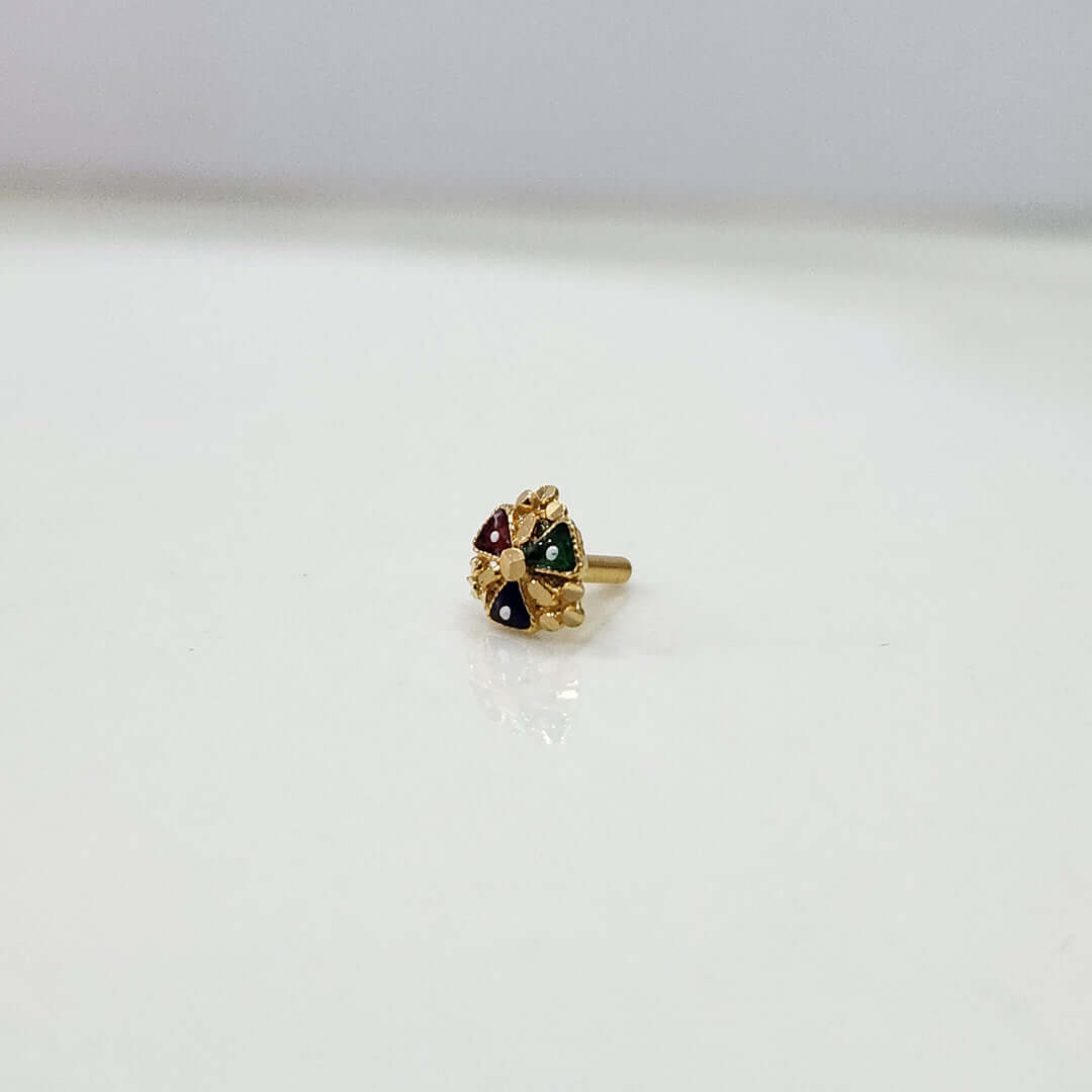 Front view of floral gold nose pin with green and red stones on a plain white surface