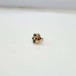Small floral 18K nose pin gold placed on a white surface highlighting delicate detailing