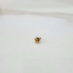 Slight angled view of a tiny gold nose pin on a white surface highlighting its fine detailing and subtle shine