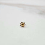 Front view of a tiny 18K gold nose pin placed on a white surface showing its compact size and fine craftsmanship