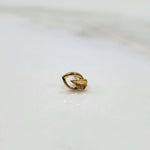 Close up of a small 18K gold nose pin placed on a white background showing fine detailing