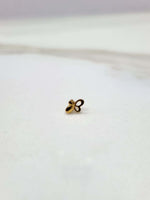Distant front view of a tiny floral 18K nose pin gold on a white background showing its minimal size and subtle shine