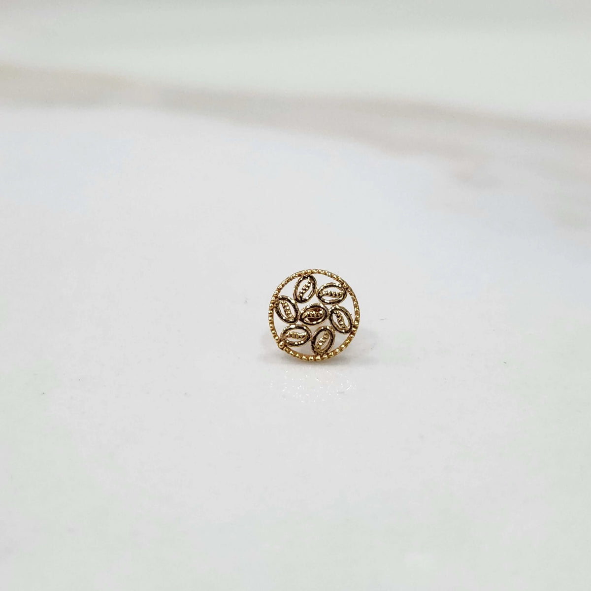 Front view of an 18K gold round nose pin on a white background displaying its floral-inspired design