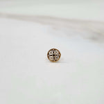Front view of a small round 18K nose pin gold placed on a white surface highlighting its compact detailing