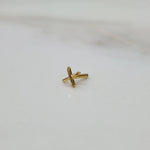 Angled close up of a small cross shaped gold nose pin on a white background highlighting fine detailing