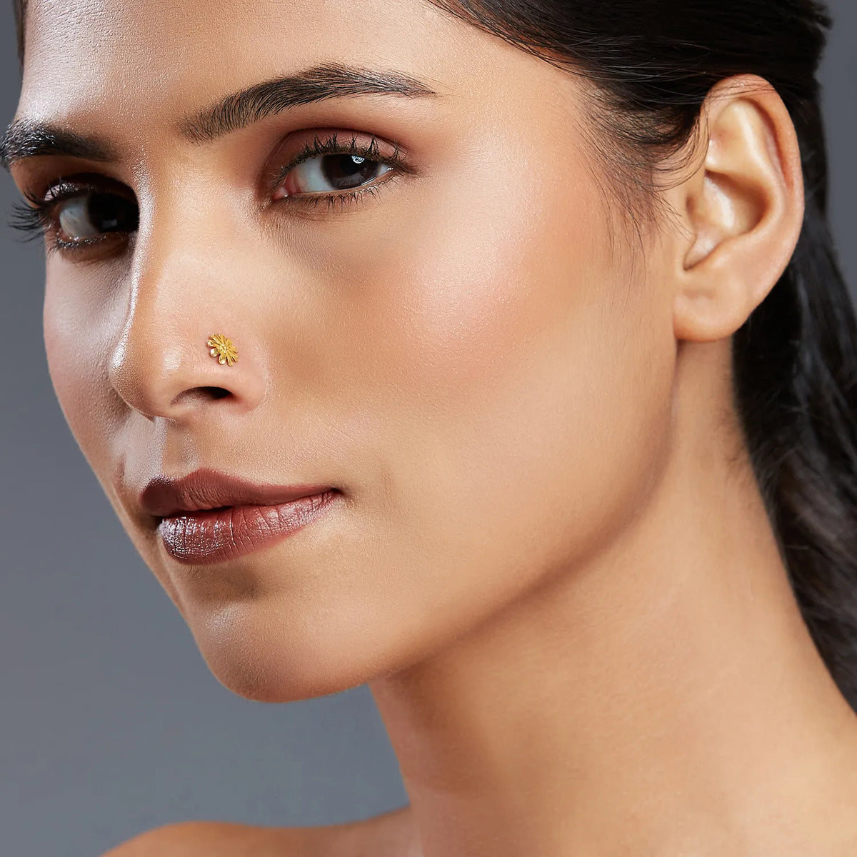 Woman wearing a small daisy design 18K gold nose pin showcasing elegant everyday styling