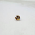 Front view of small hexagonal lattice gold nose pin placed on a white surface highlighting compact design