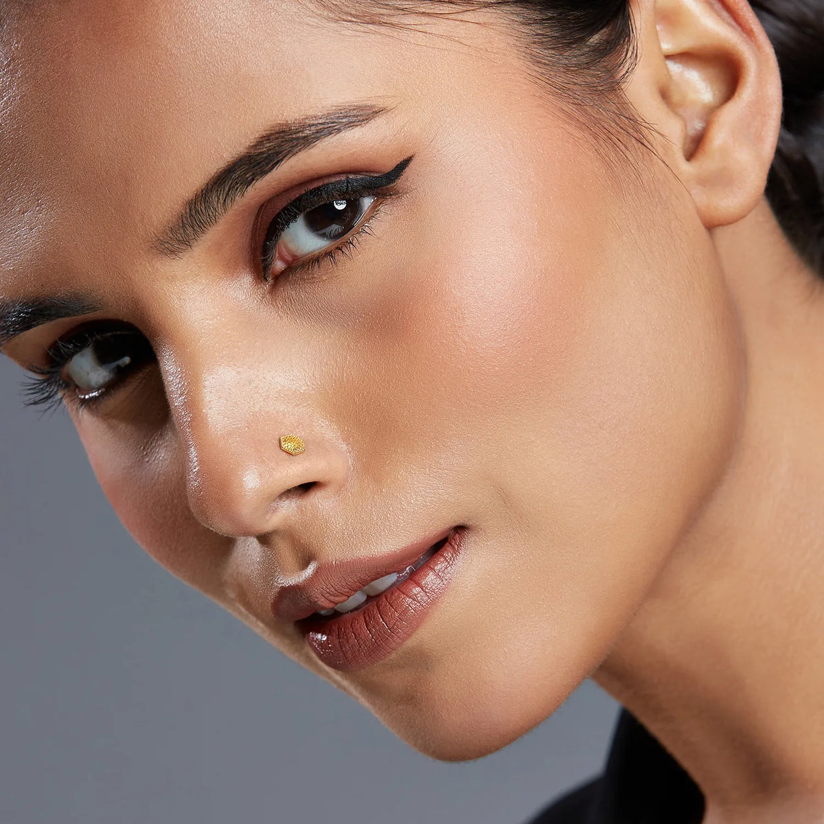 Close up portrait of woman wearing a geometric hexagon 18K gold nose pin highlighting refined facial styling