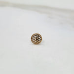 Side angled view of a round gold nose pin on a white surface showing its compact size and finish