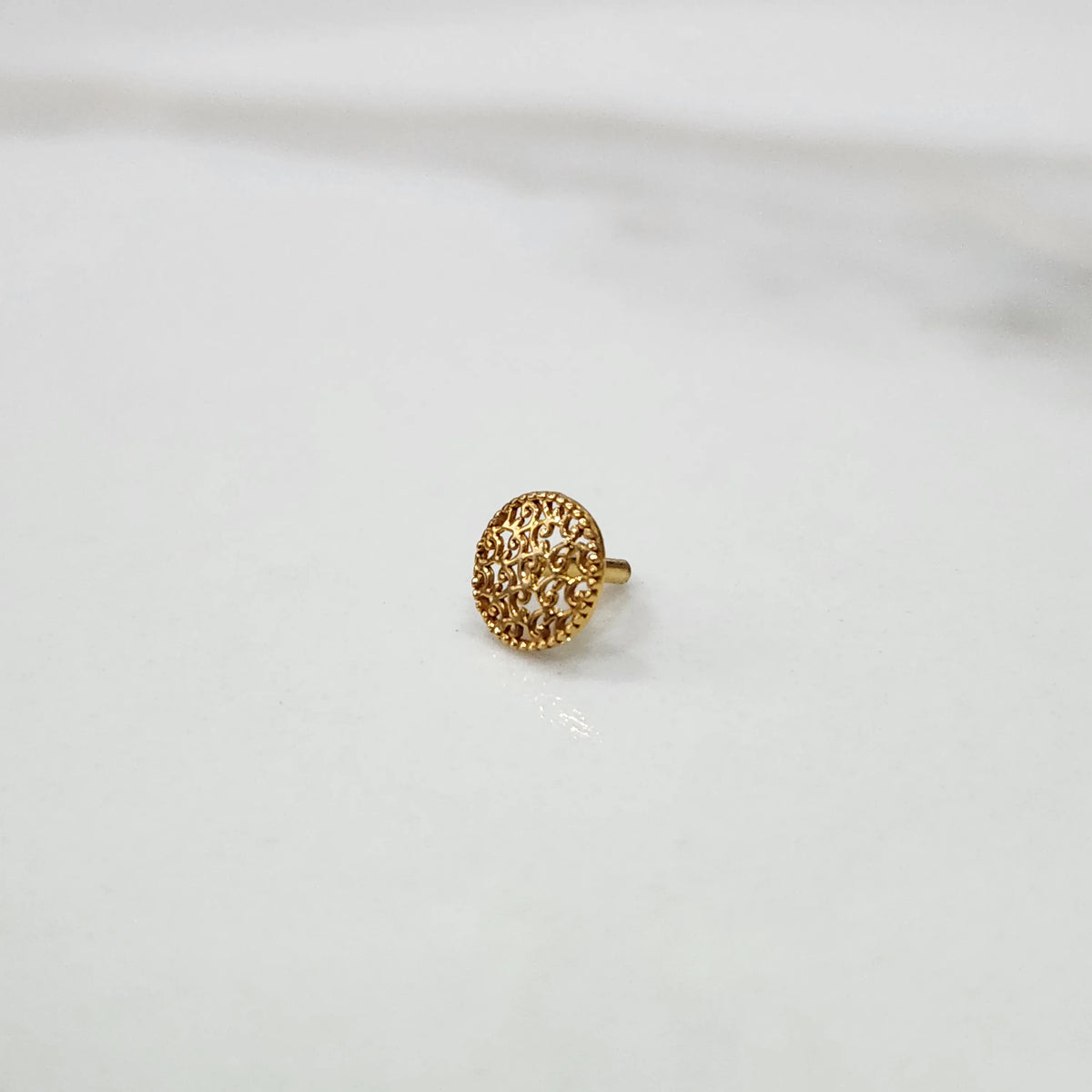 Front view of a small round gold nose pin design placed on a white background for clear design visibility