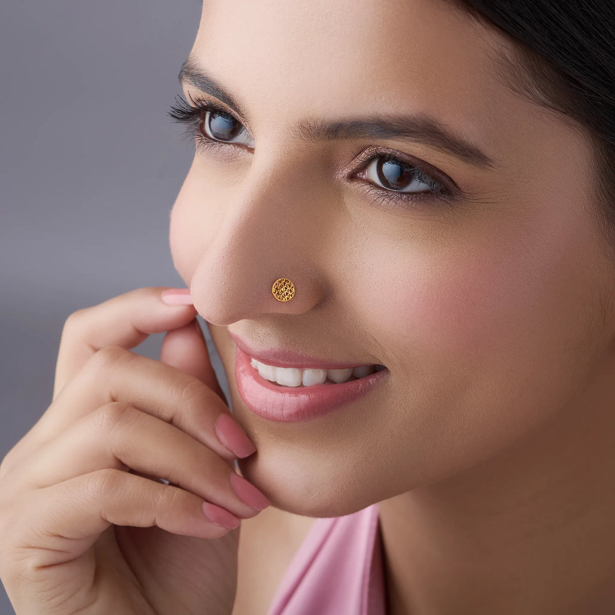 Lifestyle front view of a woman wearing a round gold nose pin showing an elegant everyday look