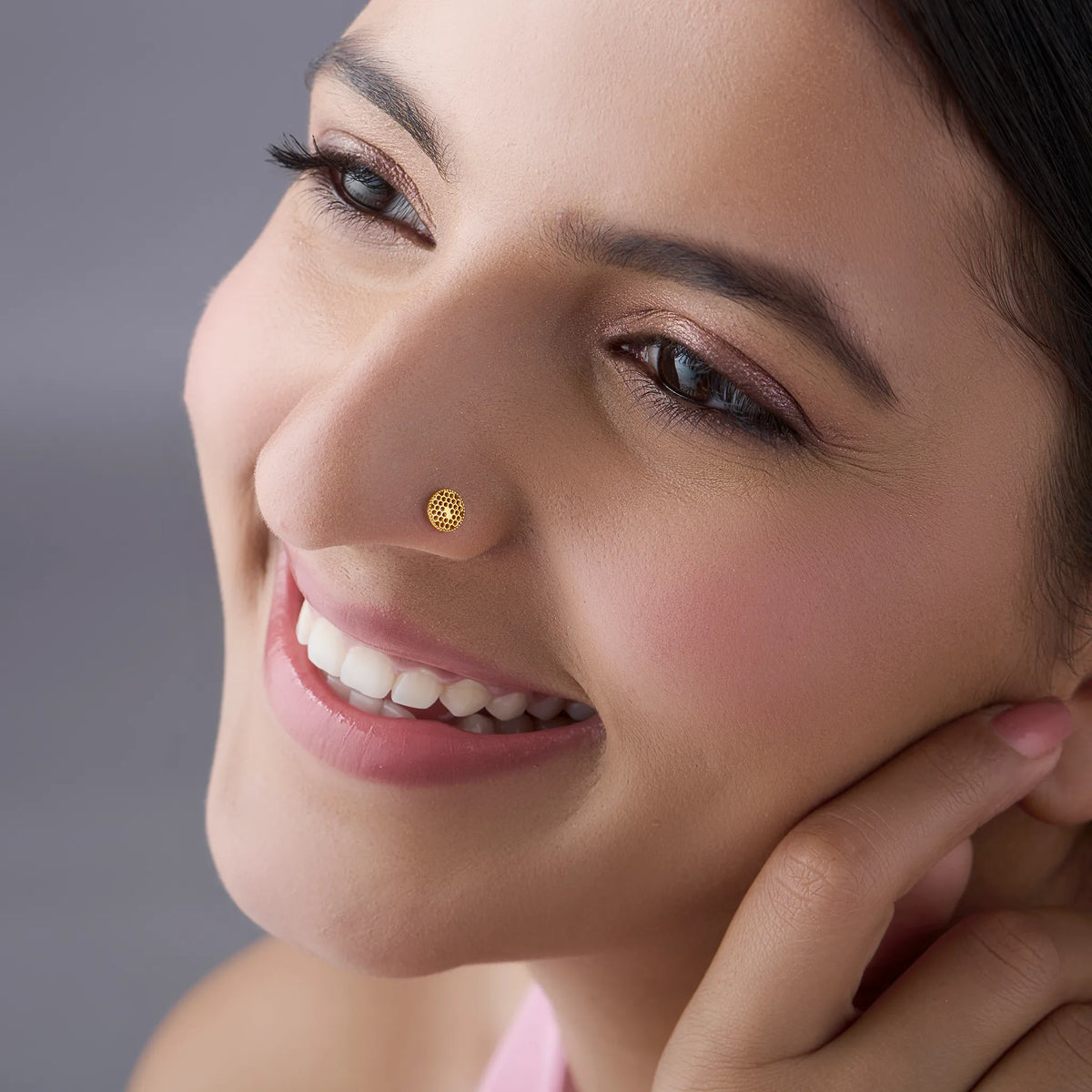 Woman wearing stylish gold nose pin design showcasing delicate round motif and elegant daily wear look