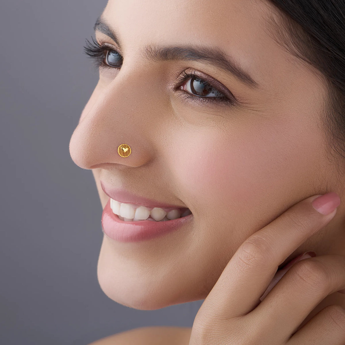 Woman wearing elegant gold nose pin design highlighting heart motif and minimal everyday look
