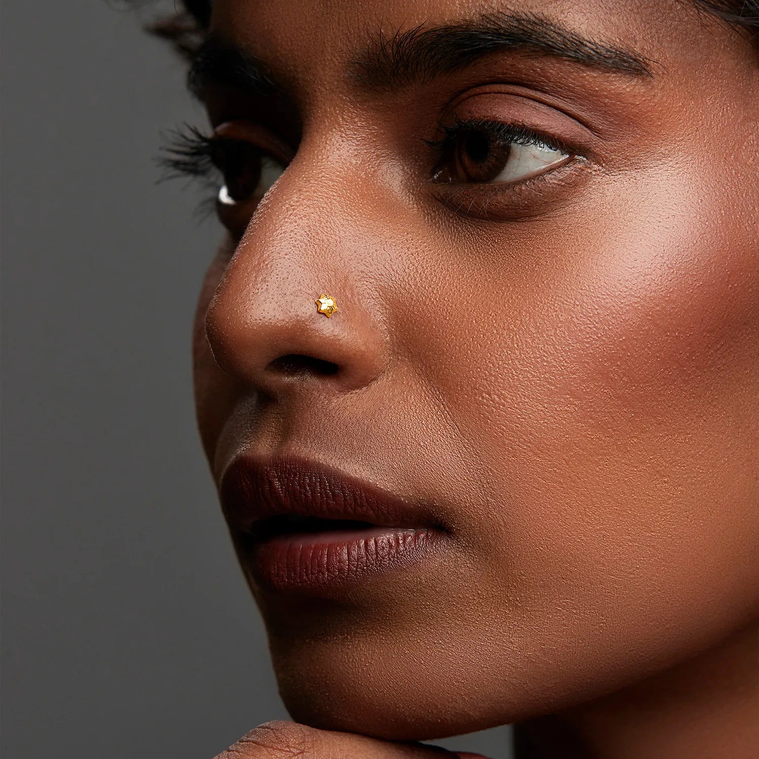 Woman wearing a delicate gold nose pin in side profile showcasing a subtle and elegant everyday look
