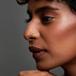 Woman wearing a minimalist gold nose pin highlighting an elegant and refined everyday look