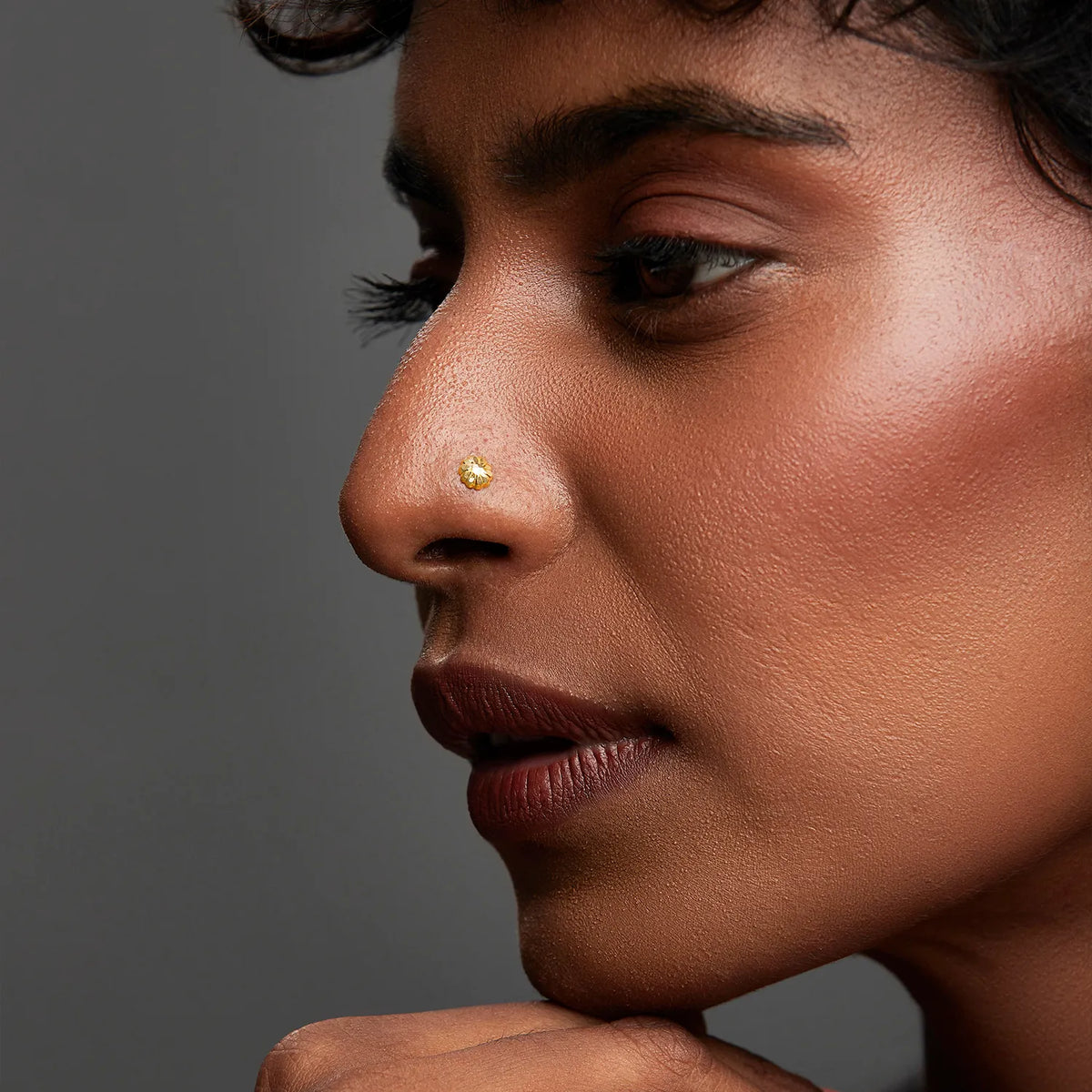 Woman wearing a minimalist gold nose pin highlighting an elegant and refined everyday look