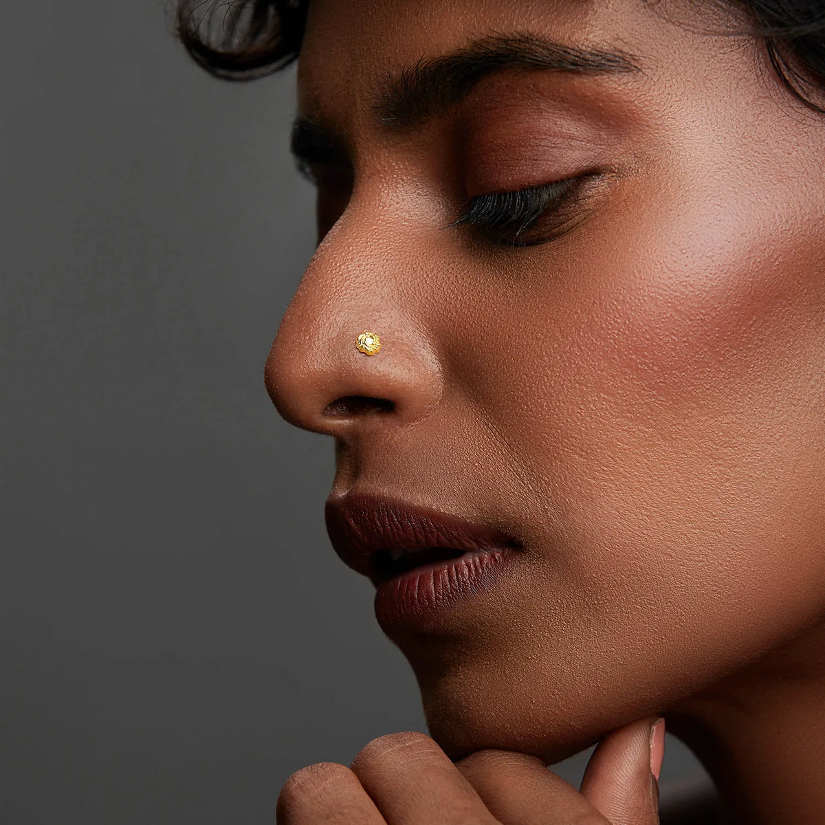 Woman wearing a small gold nose pin showing a subtle elegant side profile look